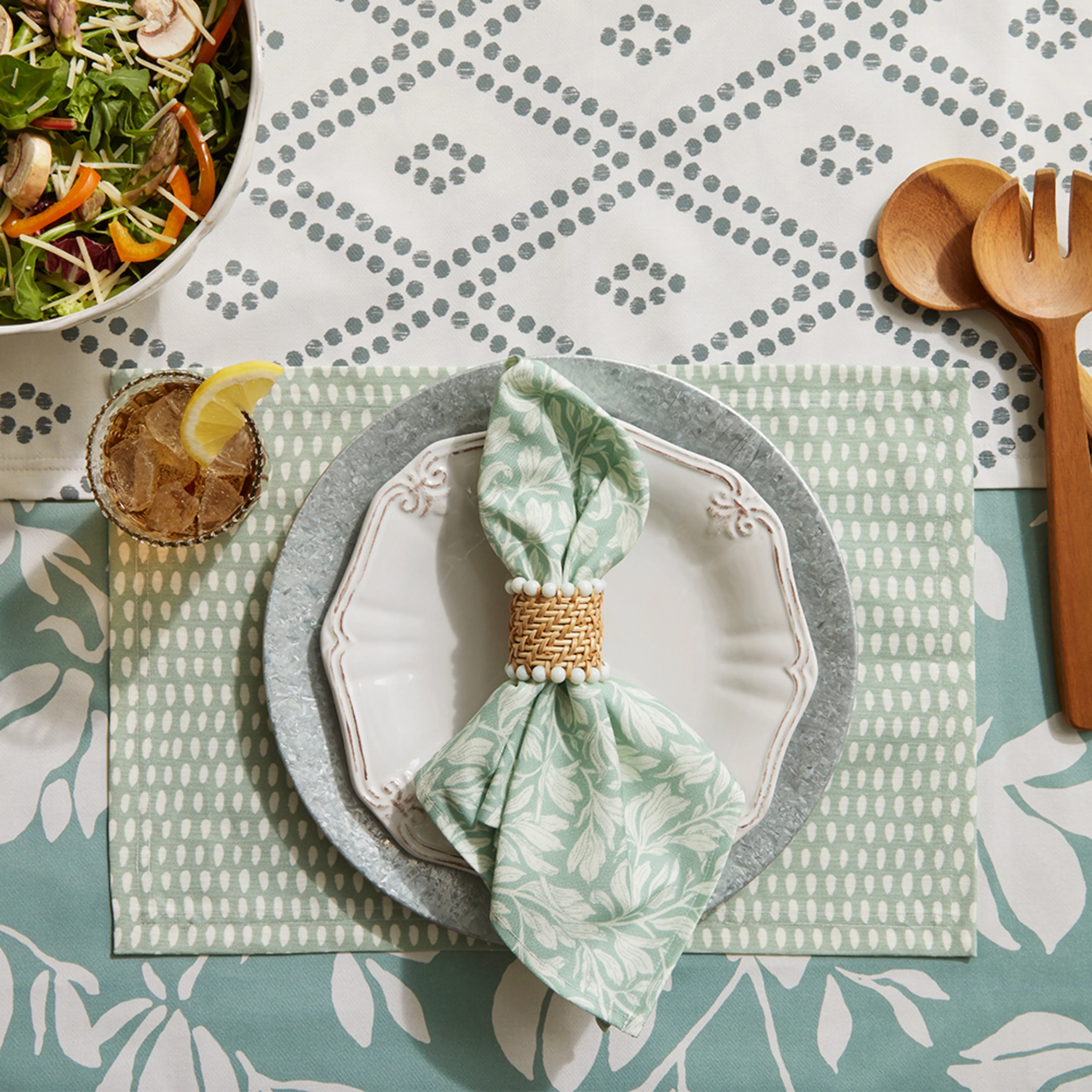 Dining table with a place setting with a teal dinner napkin and placemat.