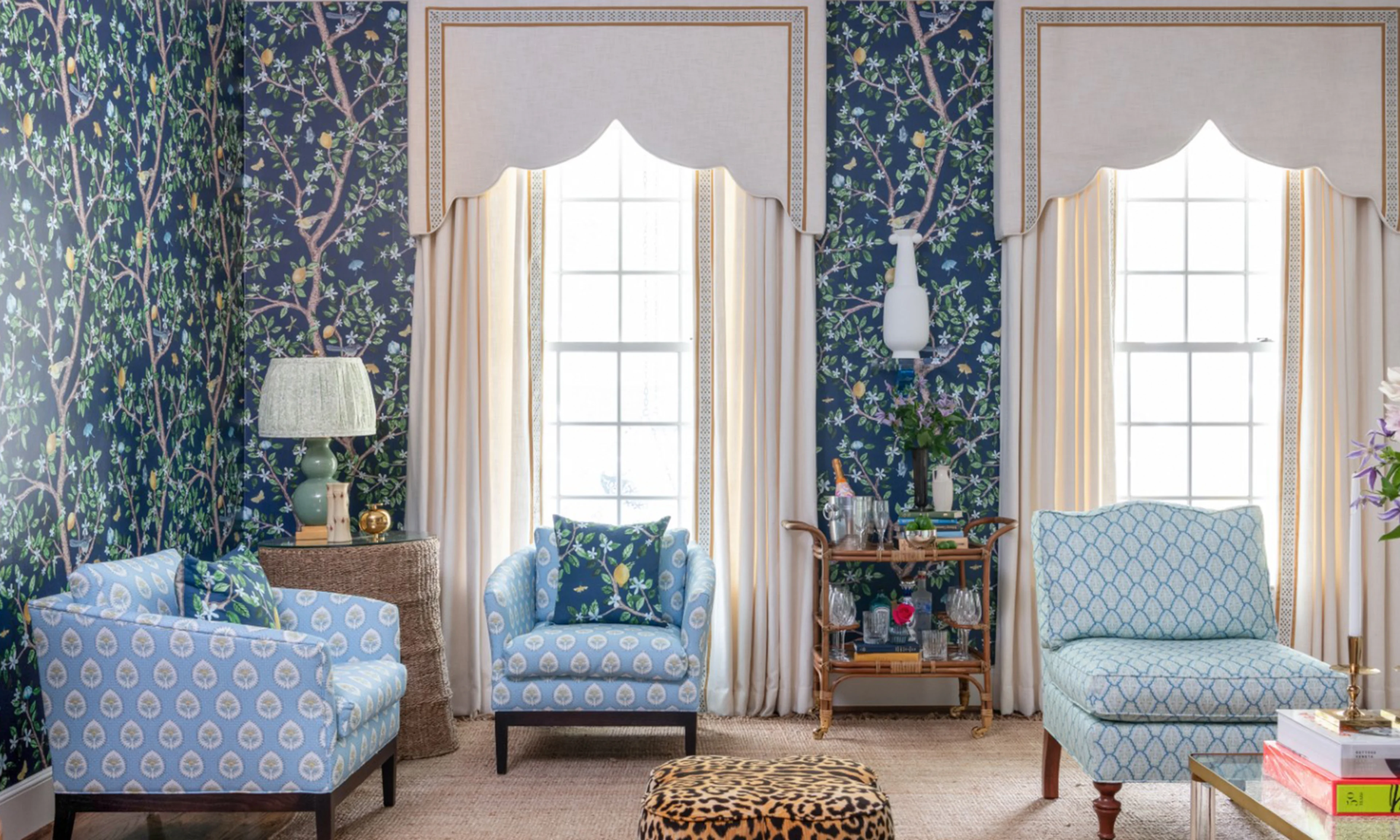 A formal living room with leopard stools and navy blue floral wallpaper.