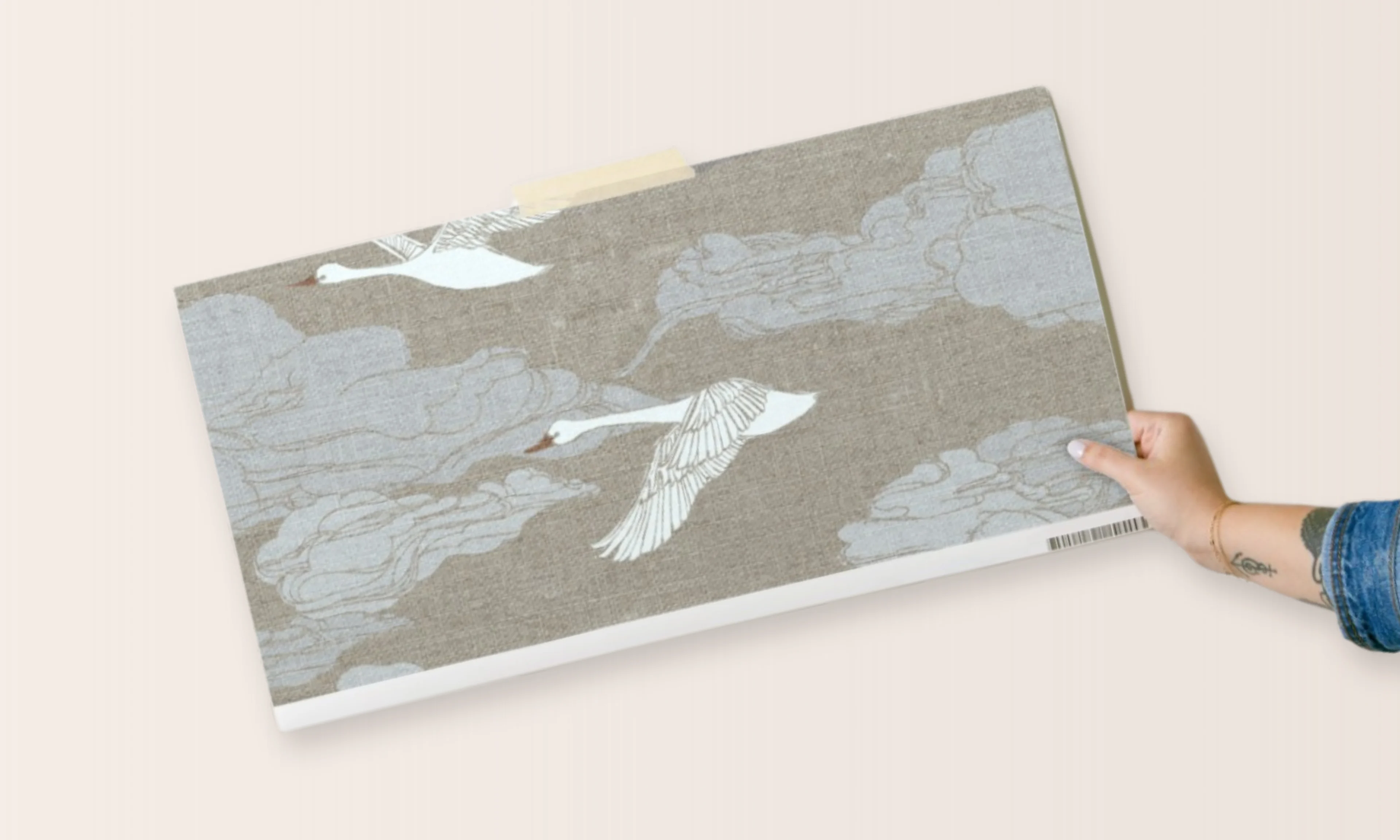 Hand holding a swan print wallpaper swatch
